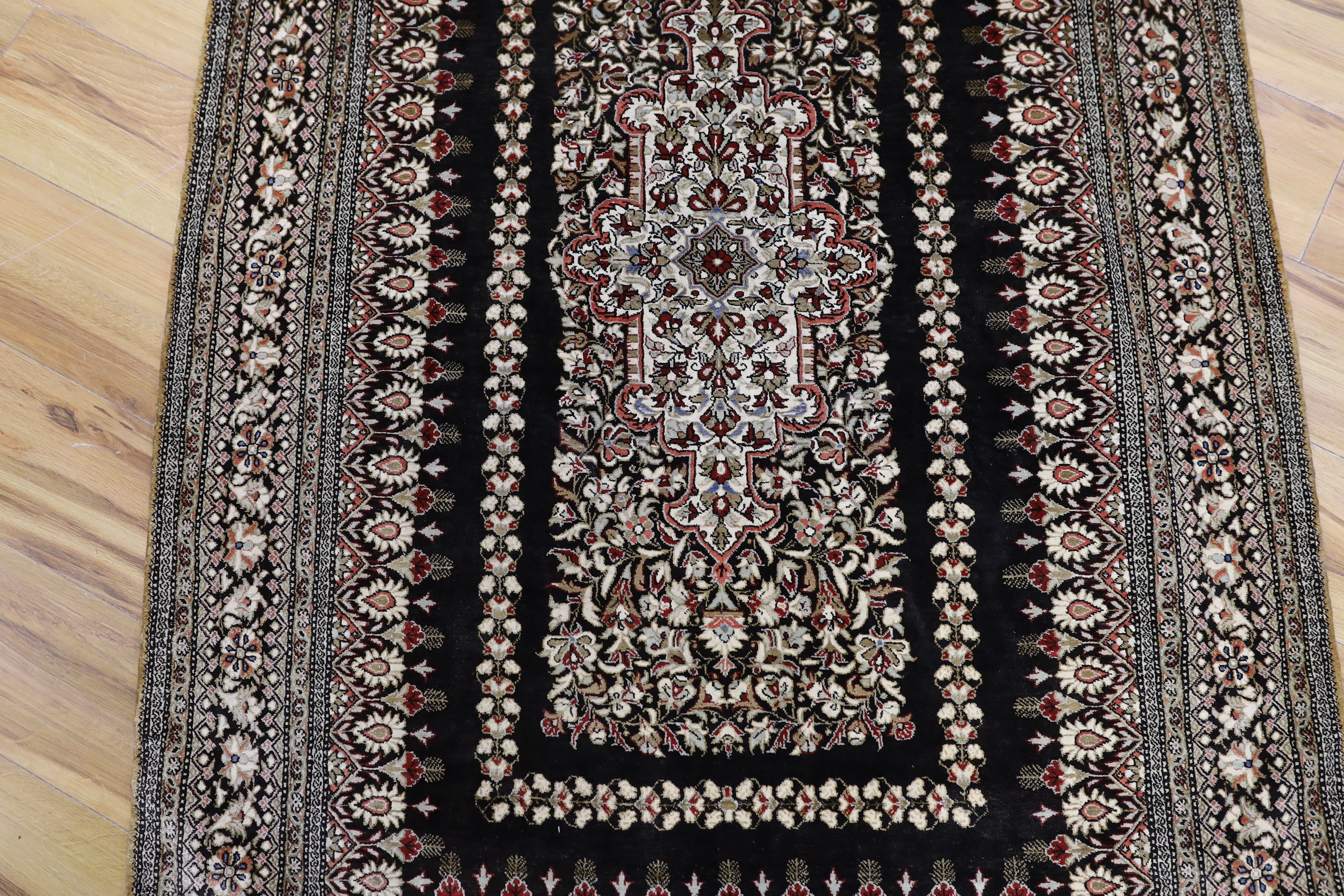 A Persian Qum silk rug, mounted as a wall hanging on a brass rod, 168 x 105cm